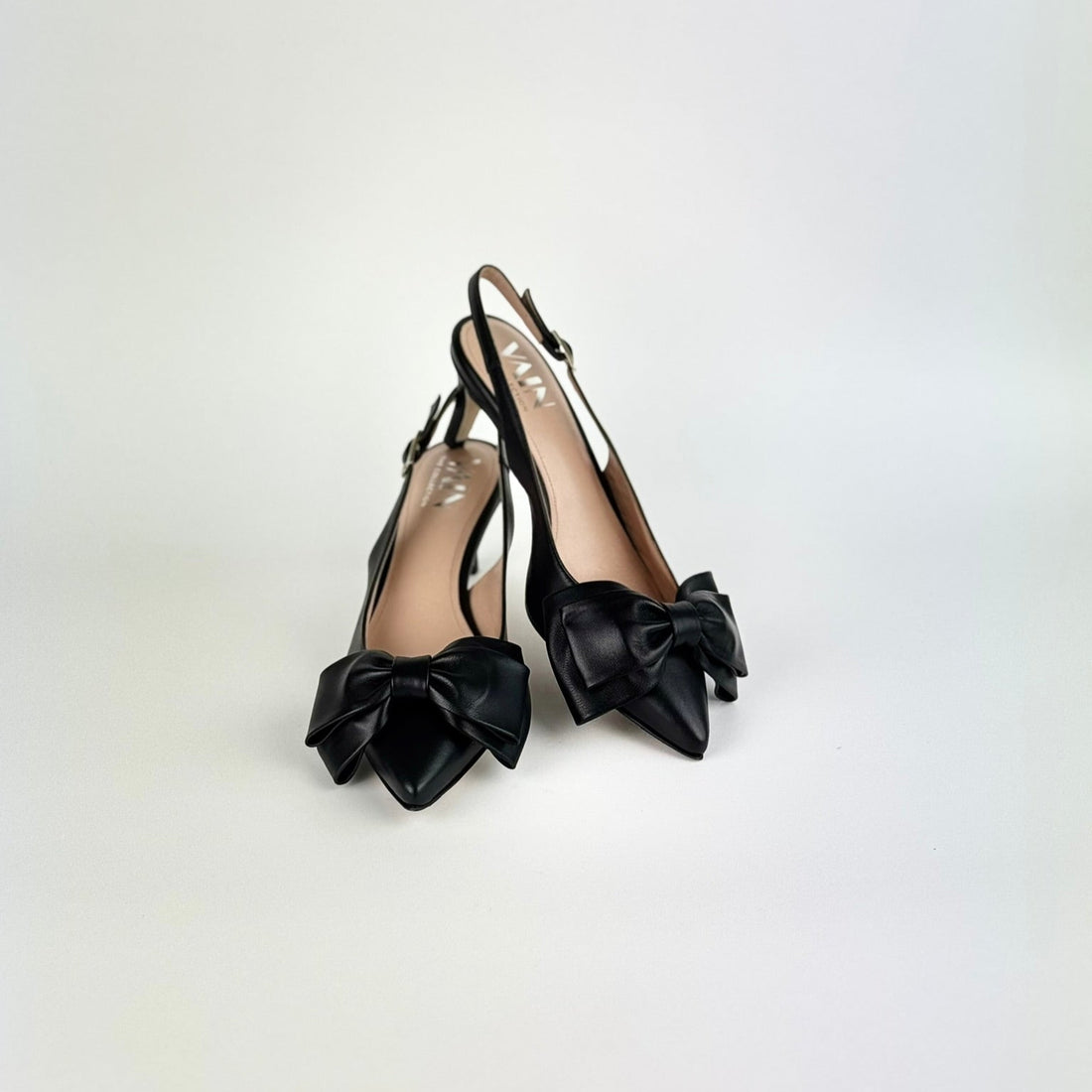 Black kitten heel sling back heels with bow details on a white background
