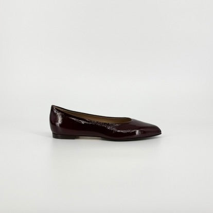 A single dark burgundy patent leather ballet flat shoe shown in profile against a clean white studio background.