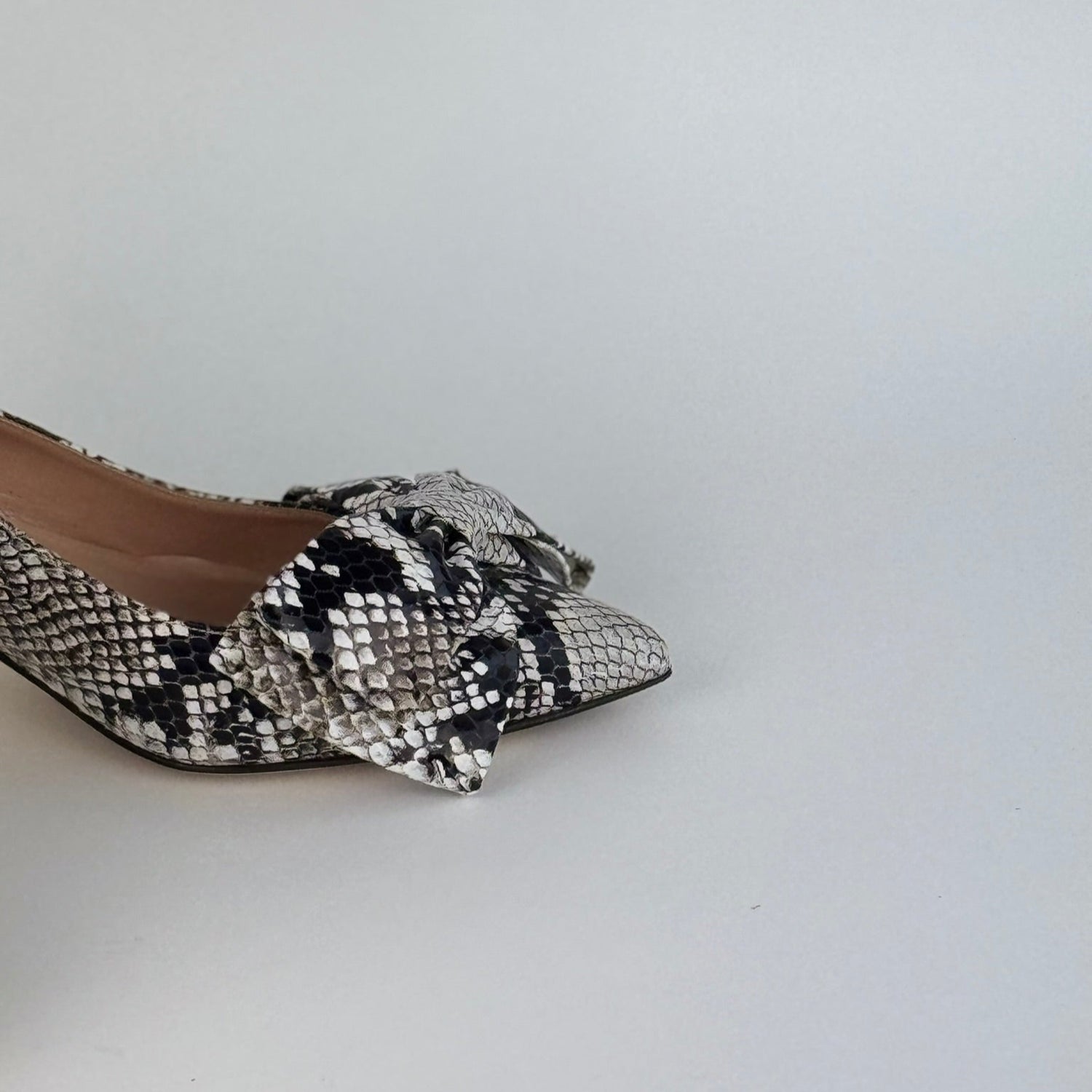 Detail of Faux Python sling back kitten heel with a bow on a white background - side view