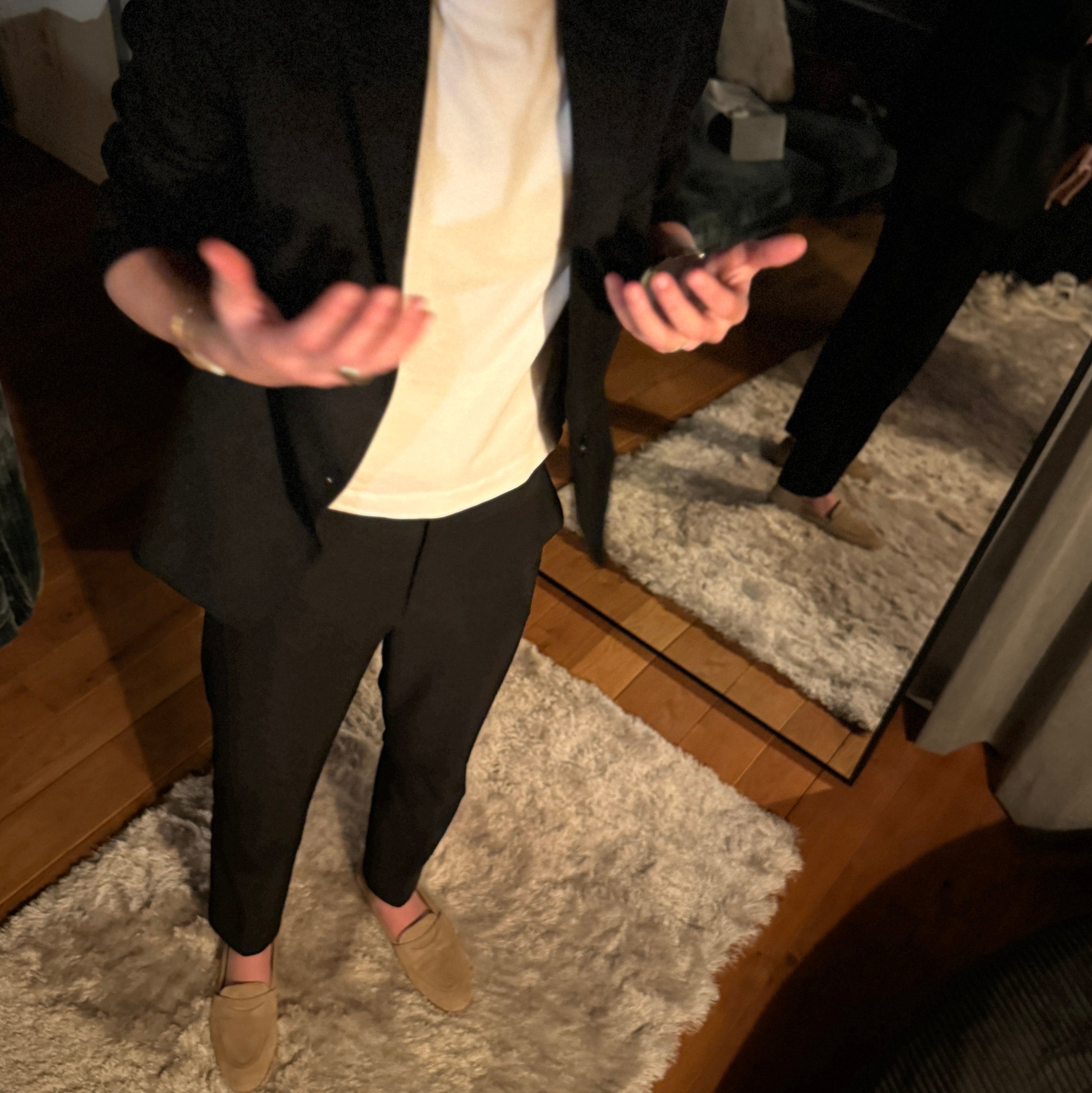 Person standing in a room with a mirror reflecting their outfit.