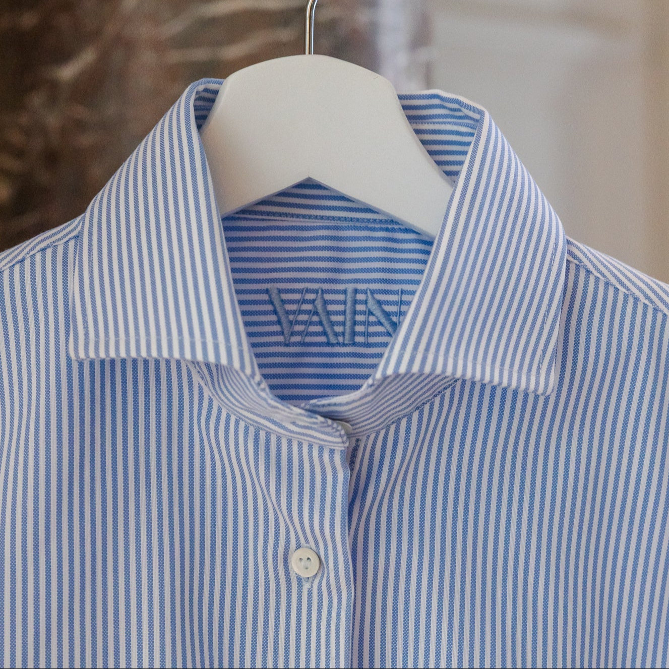 Blue and white striped shirt on a hanger with a blurred background