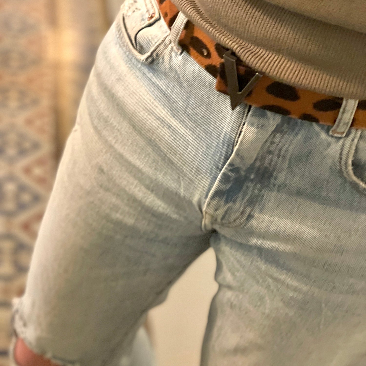 close up of woman wearing light blue jeans with leopard printed belt with dark silver buckle