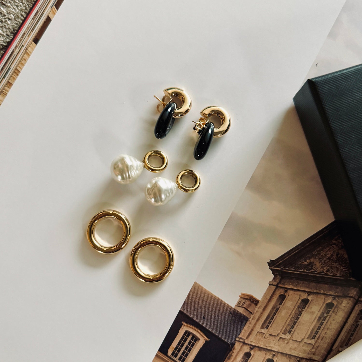 jewelry set displayed on a book with black drops, with golden hoops and large pearls