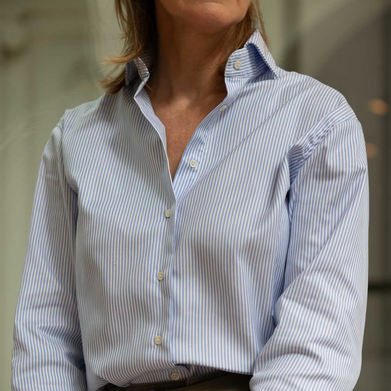 Woman wearing a blue and white striped shirt with a blurred background