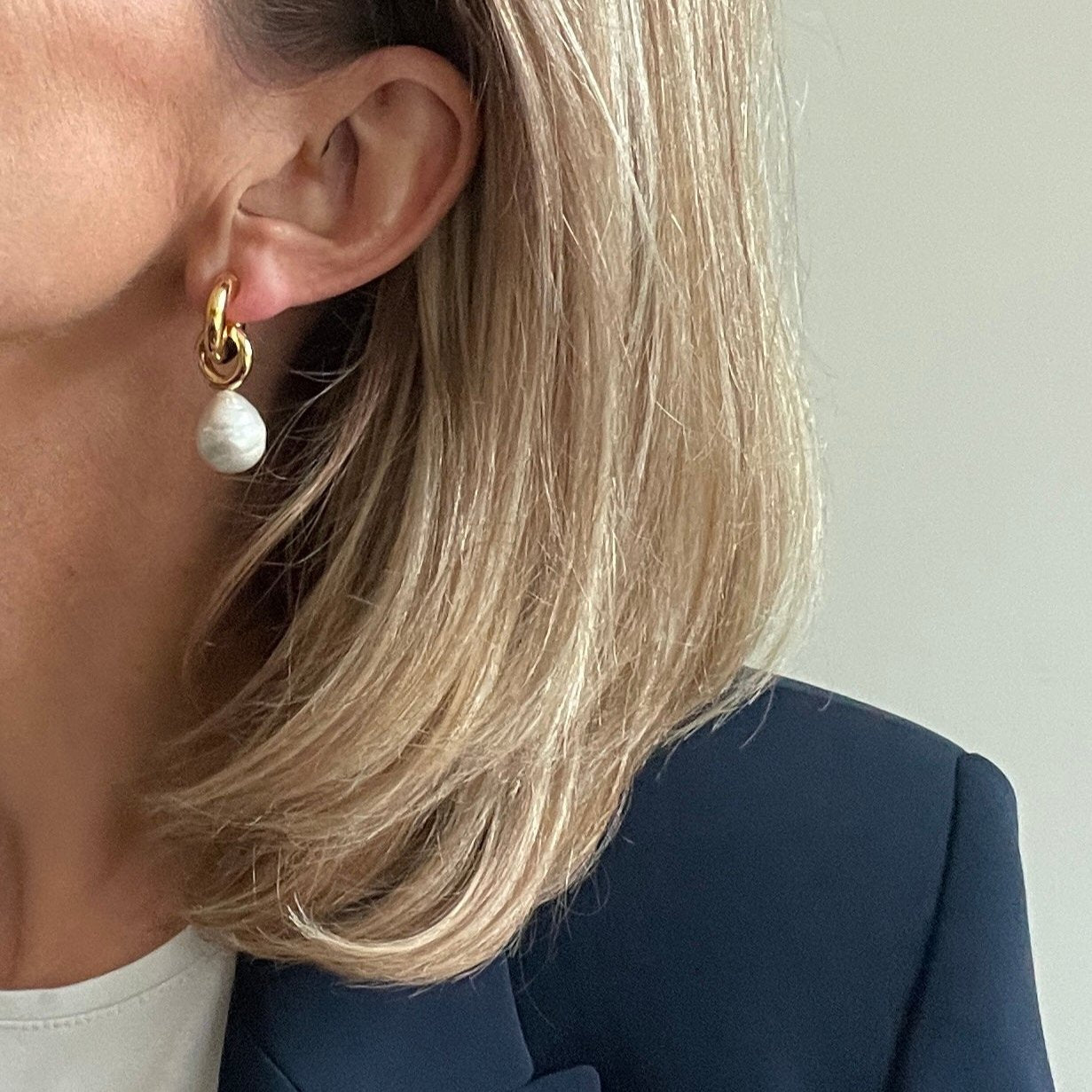 woman wearing gold earring with large pearl