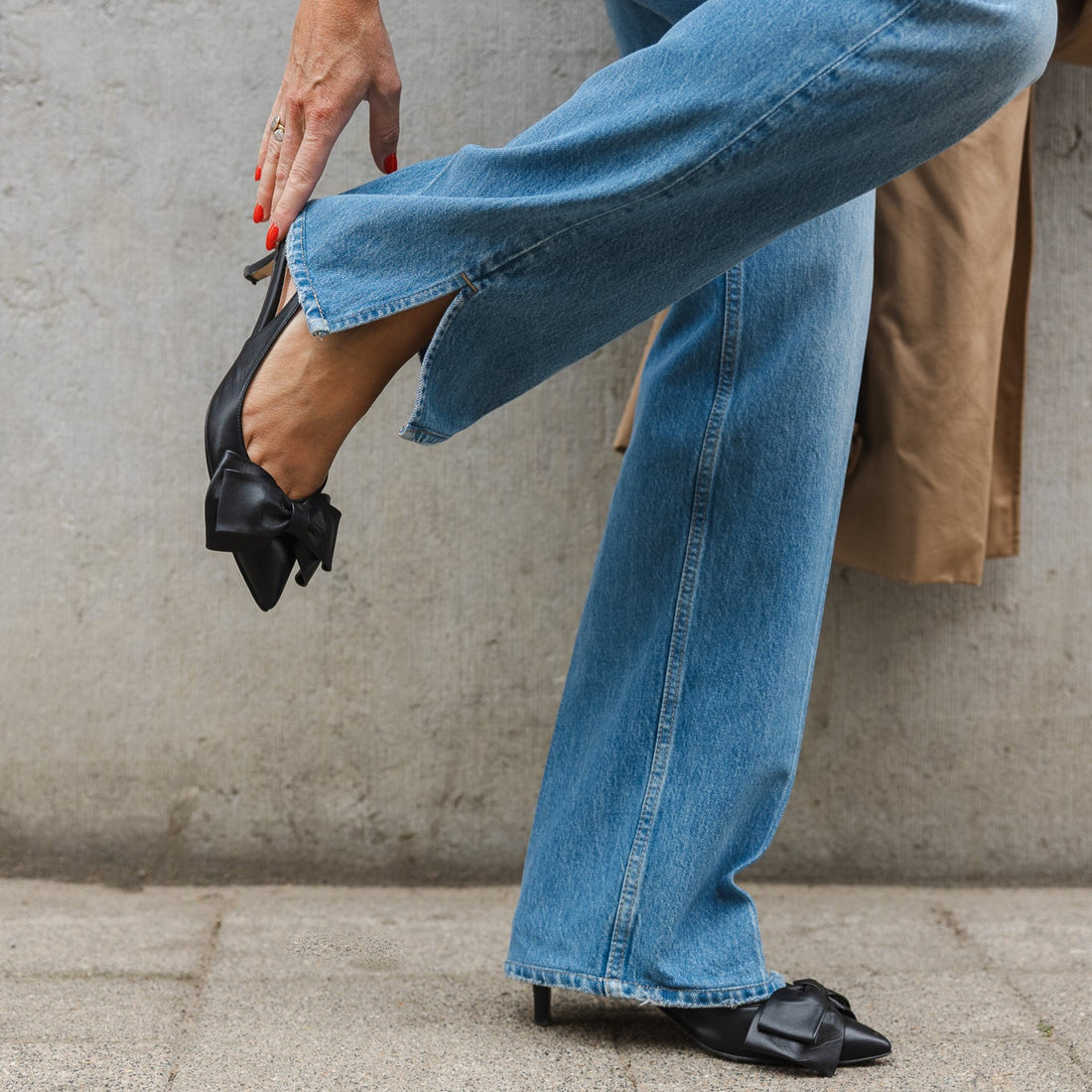 woman wearing slingback kitten heels in black nappa and blue jeans against light grey background