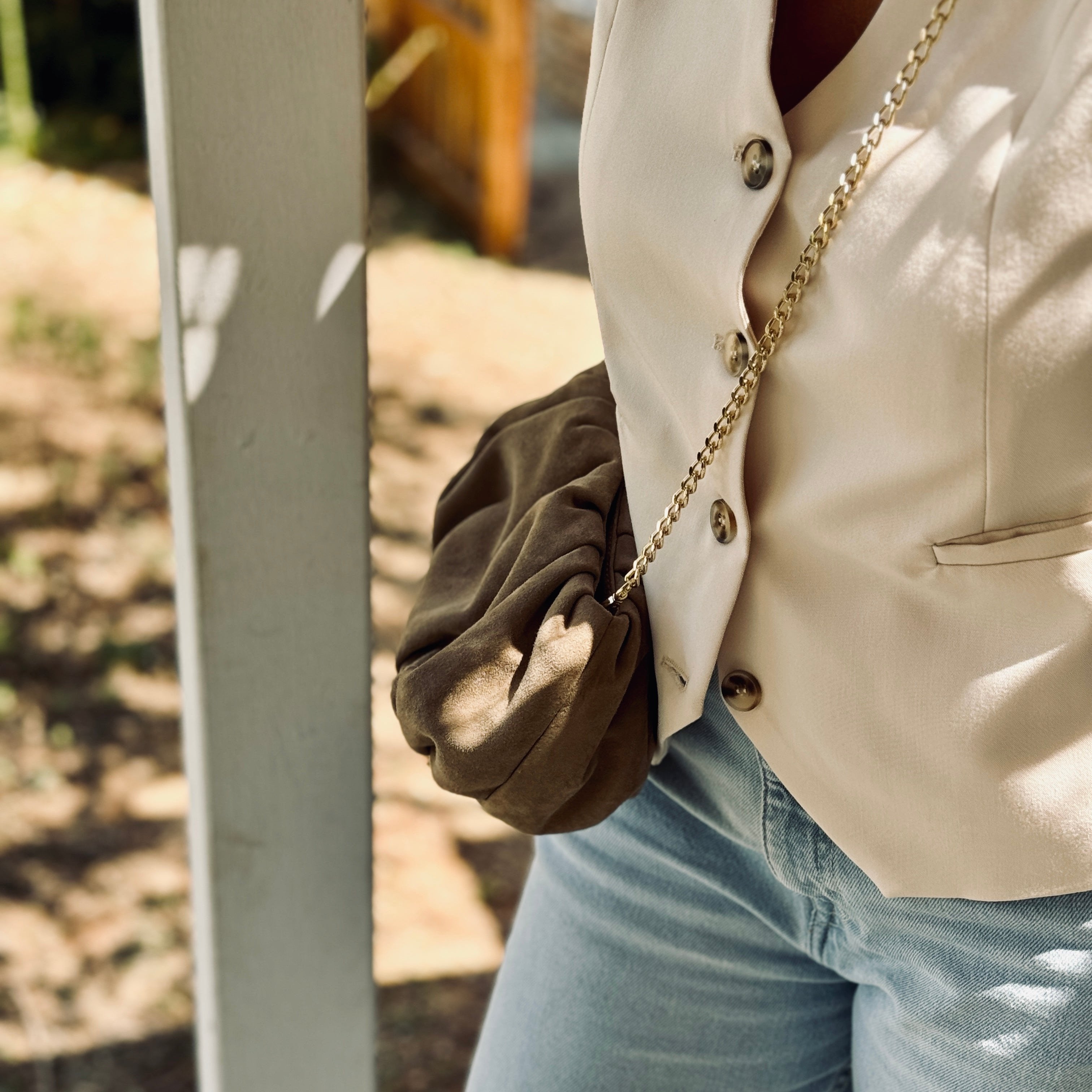 woman in summer outfit wearing the sandbeige suede clutch like a crossbody bag