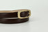 A close-up of a dark brown leather belt with a polished gold-tone metal buckle, showing the inner tan lining, set against a plain light gray background.