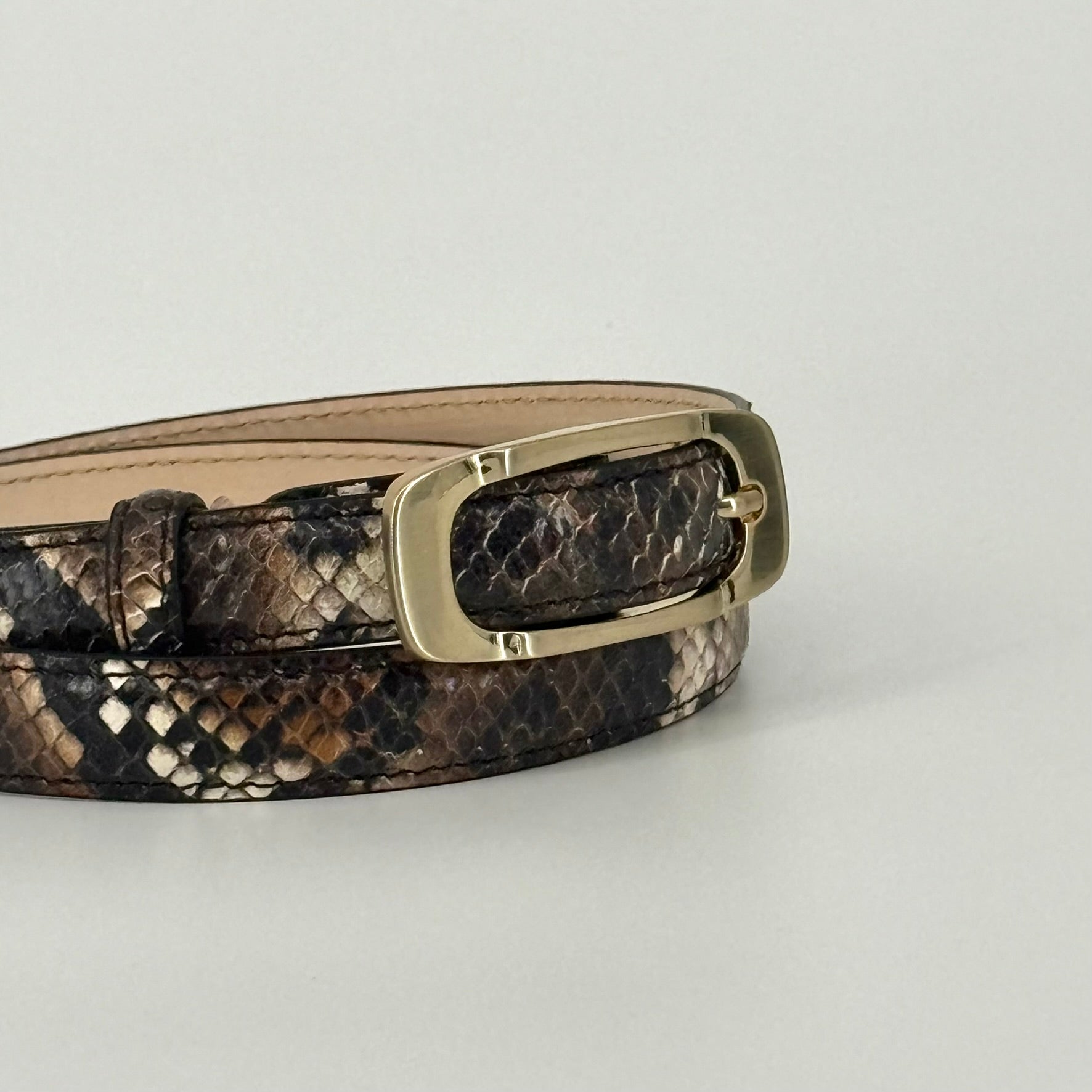 A close up of a brown and black snakeskin-patterned belt with a bronze-toned metal buckle, displayed on a clean white background.