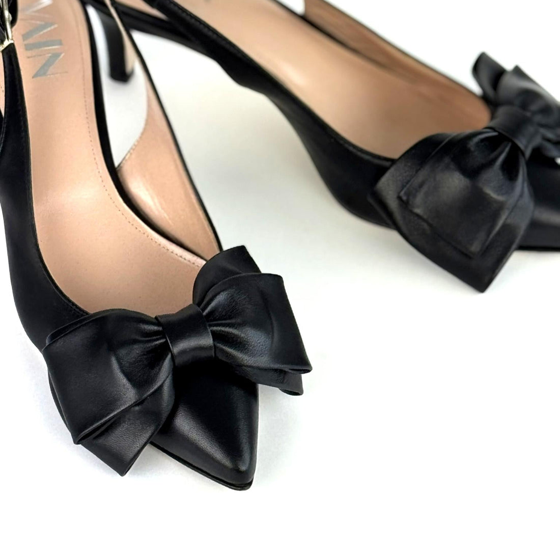 Black low-heeled slingback shoes with bow details on a white background