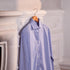 Blue striped shirt hanging on a hook against a decorative wall.