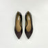A pair of pointed-toe ballerinas in a glossy dark bordeaux/plum-brown patent leather, shown from a top-down view on a light gray background. The brand name &