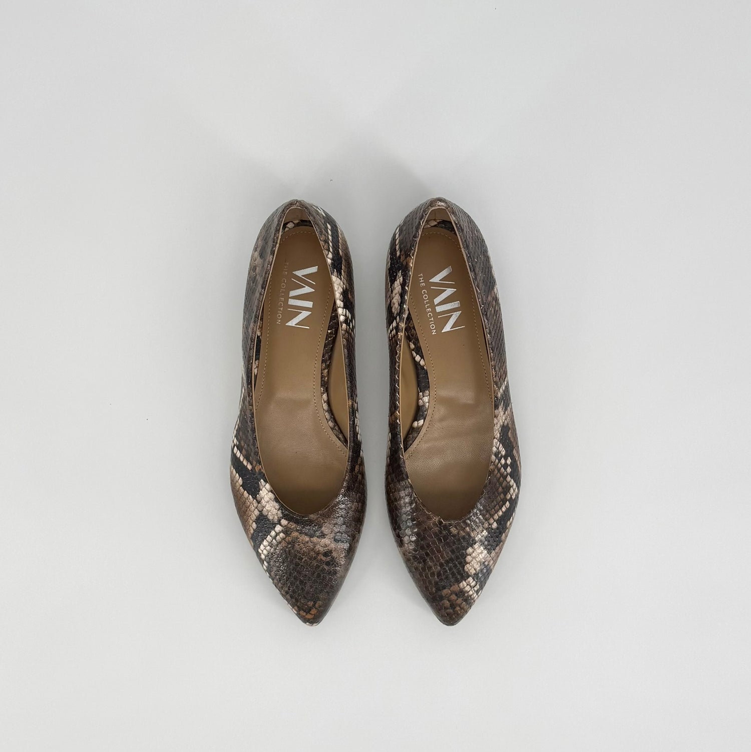 A pair of pointed-toe flats with a brown, black and beige snakeskin pattern, shown from a top-down view on a light gray background. The brand name &