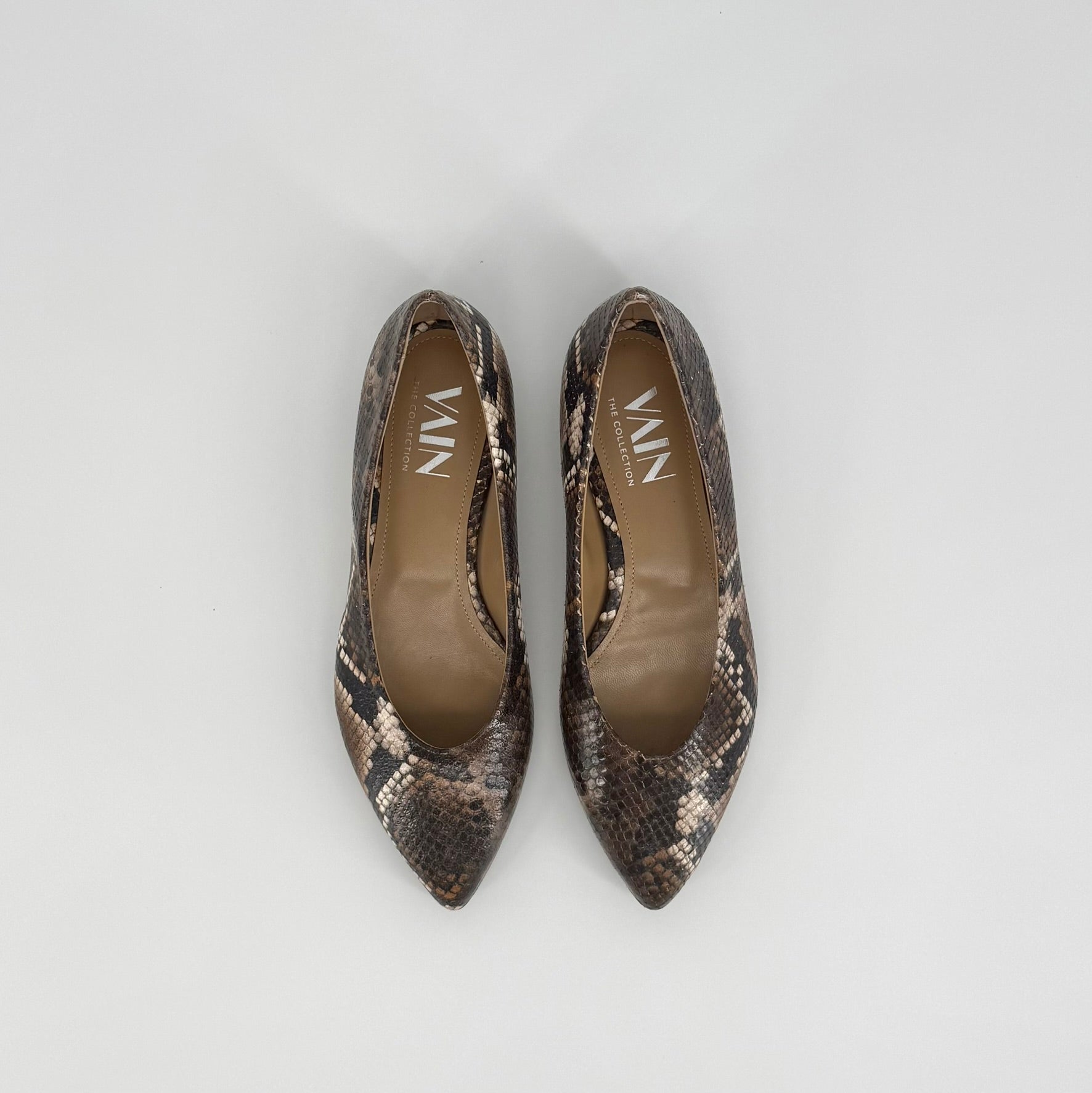 A pair of pointed-toe flats with a brown, black and beige snakeskin pattern, shown from a top-down view on a light gray background. The brand name &