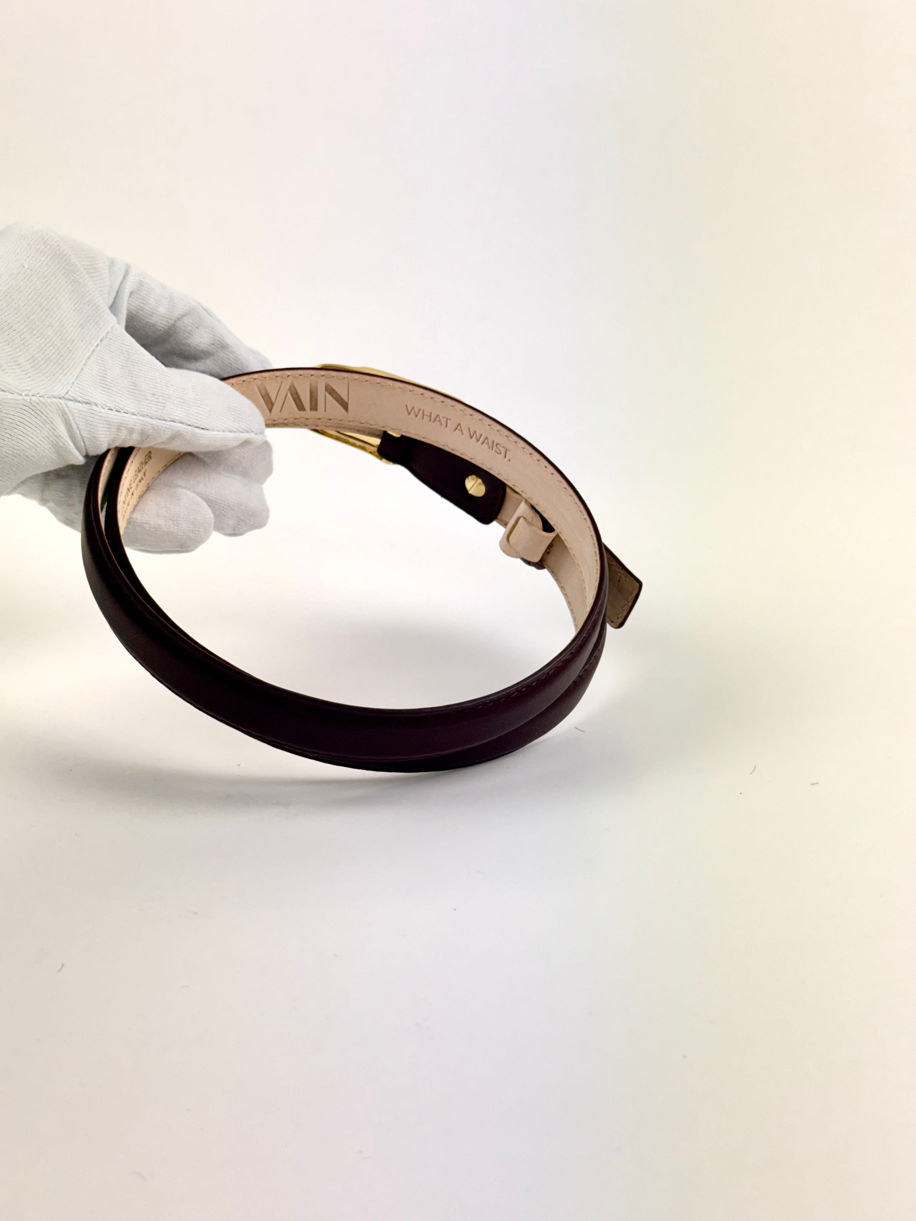 Detail of burgundy belt with golden buckle