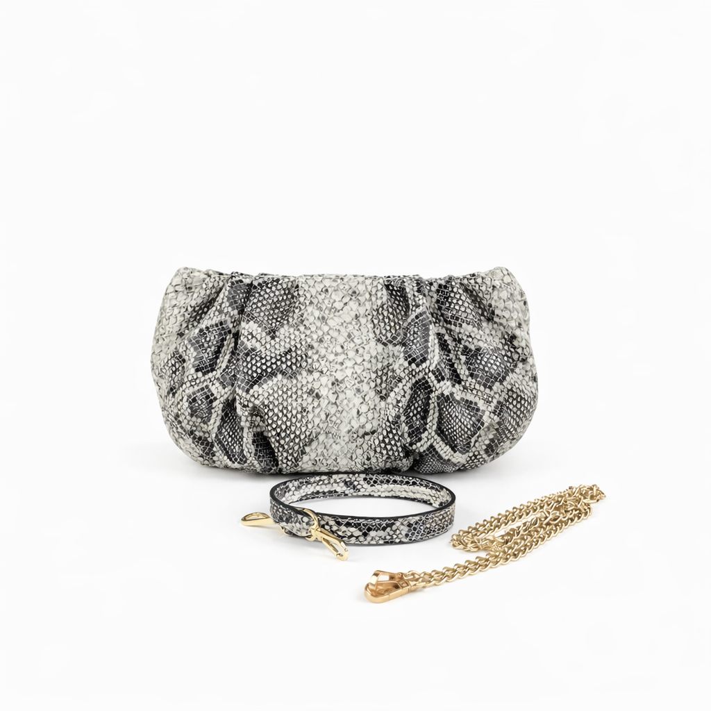 Faux Python textured clutch with wrist strap and chain on a white background