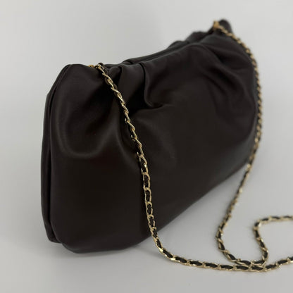 Large soft nappa leather clutch in dark brown with metallic strap on a white background