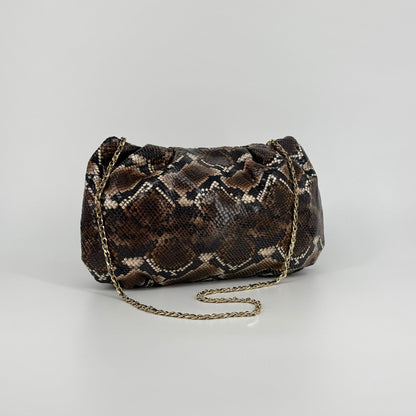 large clutch bag in a feminine folded shape in brown and black python printed leather with metallic strap on a white background