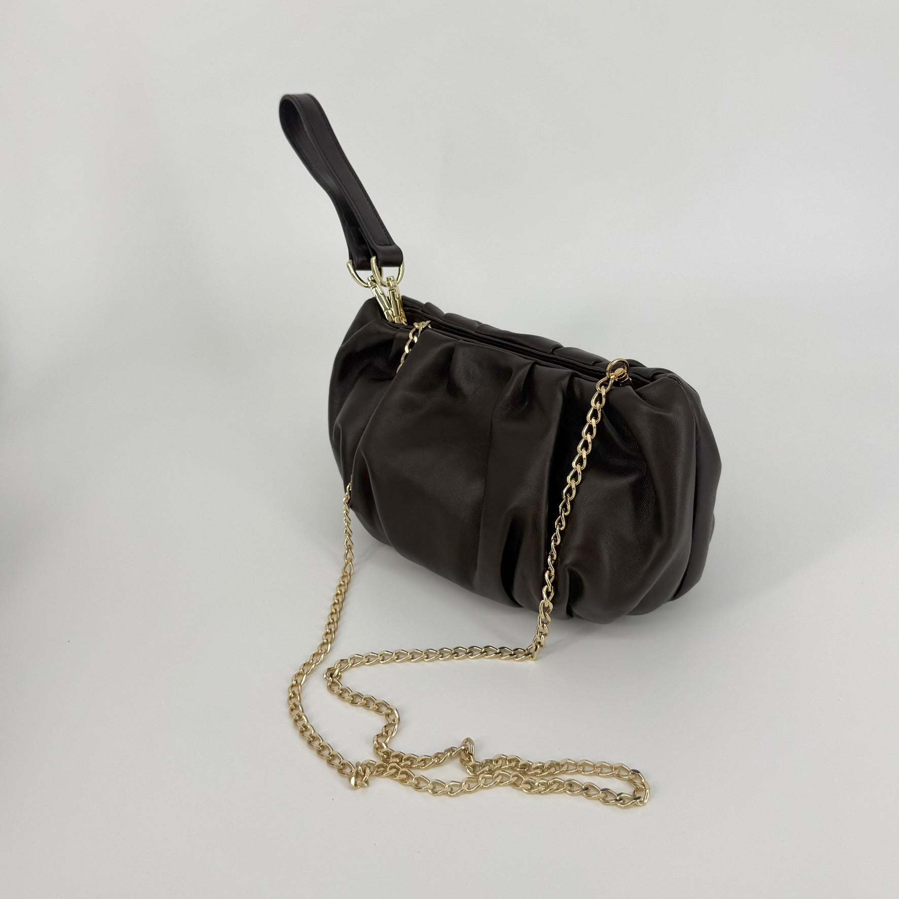 A dark brown pleated nappa leather clutch handbag with a gold chain strap and a dark brown wristlet strap, displayed on a light gray background.