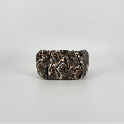 A small clutch bag with a brown and black snakeskin pattern, photographed against a neutral light gray background.