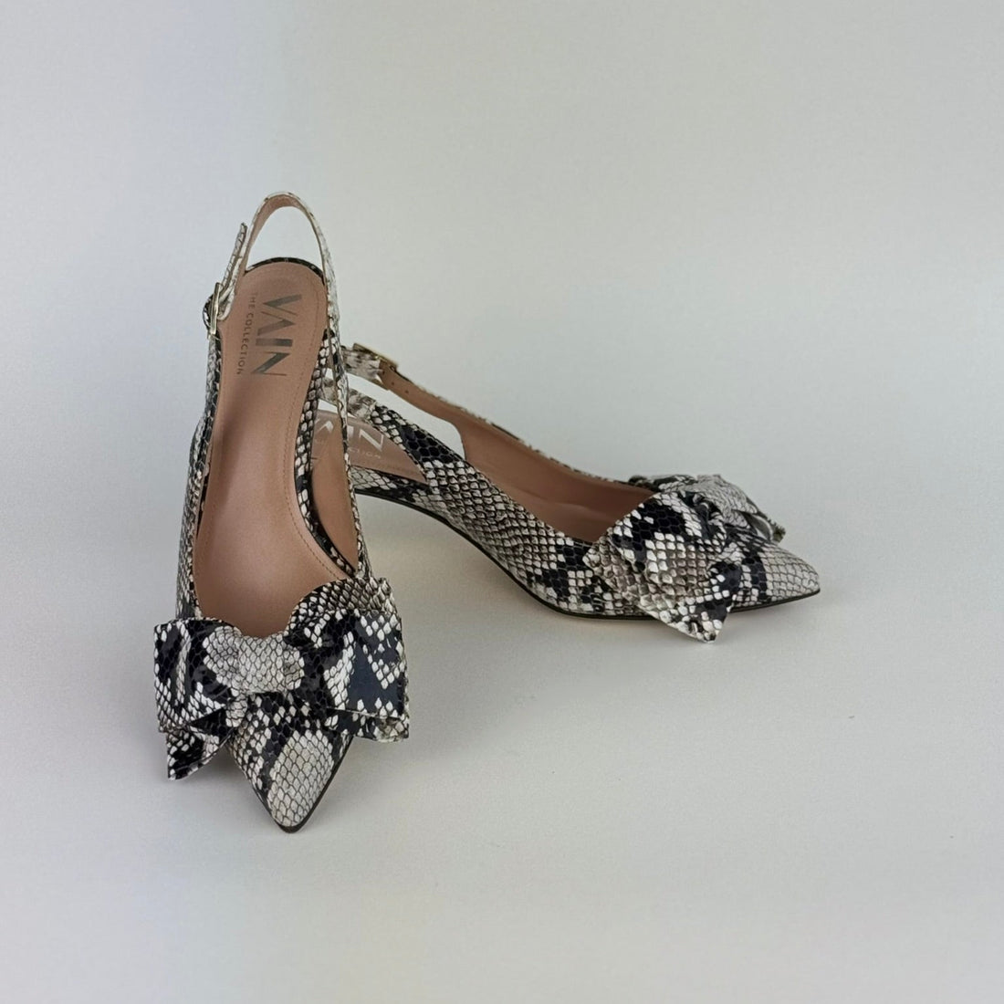 Pair of faux python slingback kitten heels on a white background