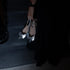 Person holding a set of silver low heels kitten sling backs in a dark setting