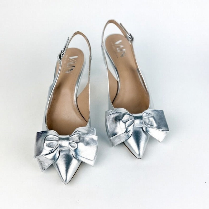 Silver low-heeled shoes with large bows on a white background
