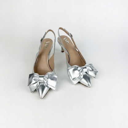 Silver low-heeled shoes with bow details on a white background