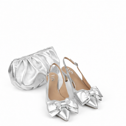 Silver shoes with bow details and a matching clutch on a white background
