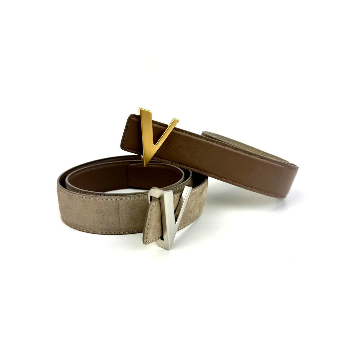 Two reversible belts with gold and silver buckles on a white background