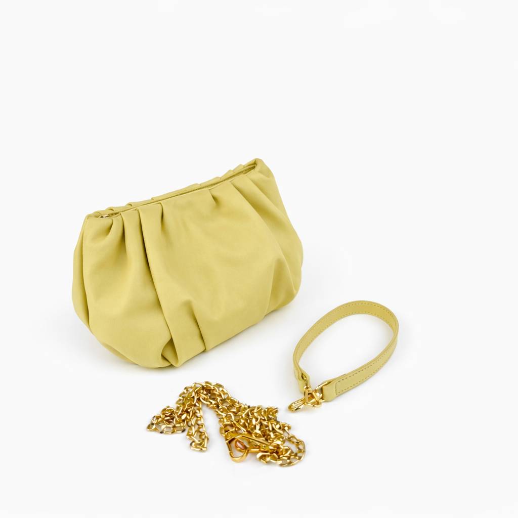 Yellow clutch bag with a gold chain and leather wriststrap on a white background