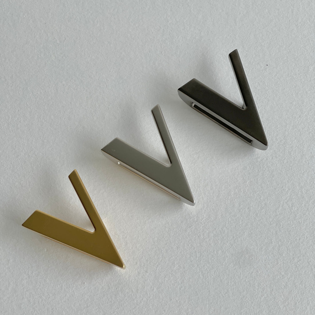 a gold brushed buckle a silver brushed buckle and a dark silver brushed buckle top view