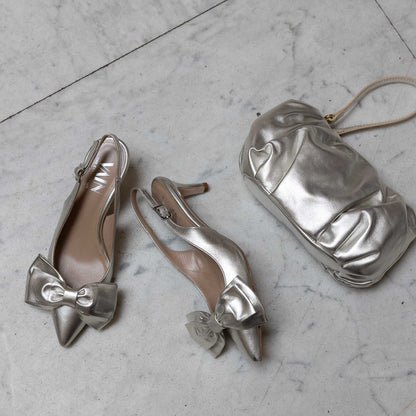 champagne coloured clutch and kitten heels on marble floor