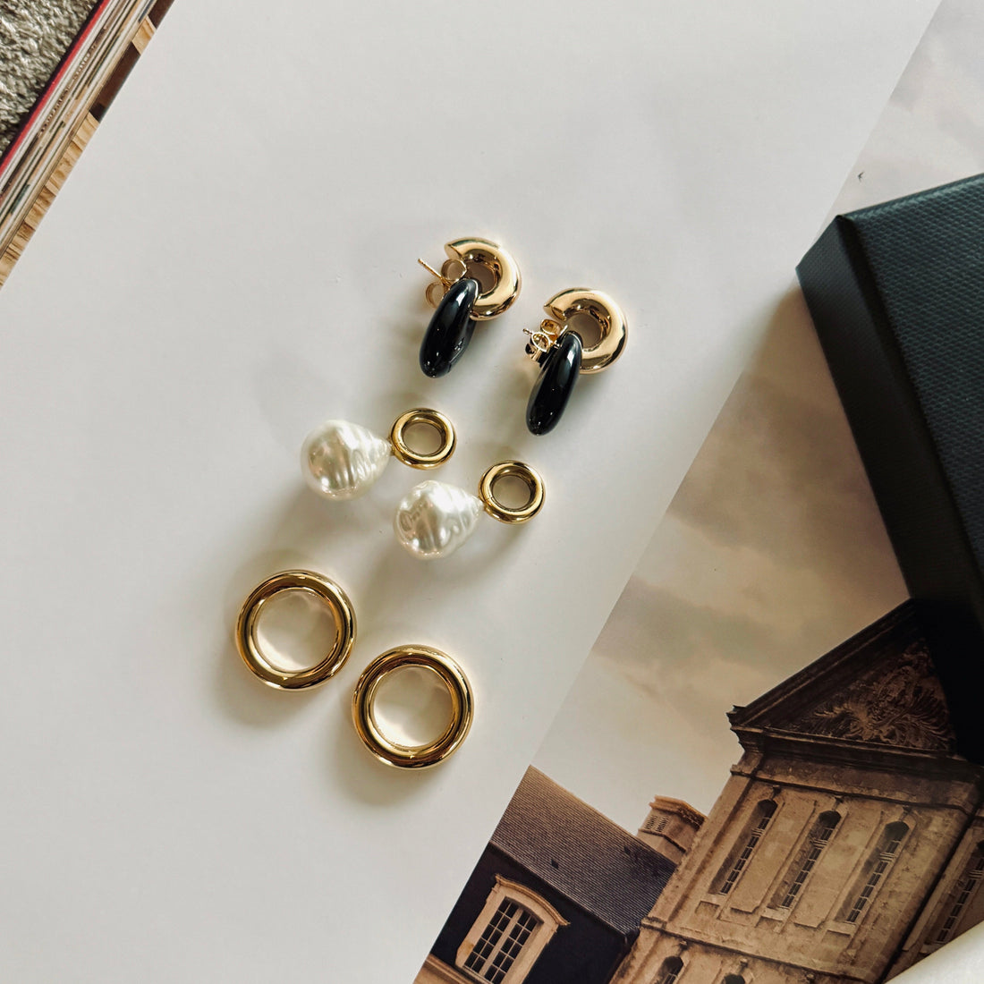 jewelry set displayed on a book with black drops, with golden hoops and large pearls