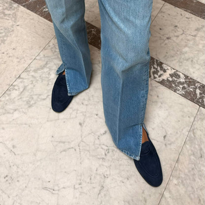 woman wearing blue jeans and navy loafers on a marble floor