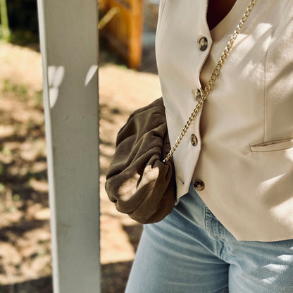 woman in summer outfit wearing the sandbeige suede clutch like a crossbody bag